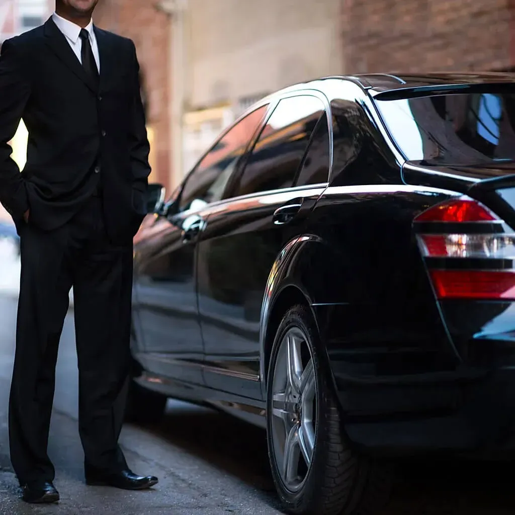 Chauffeur beside a black luxury limousine